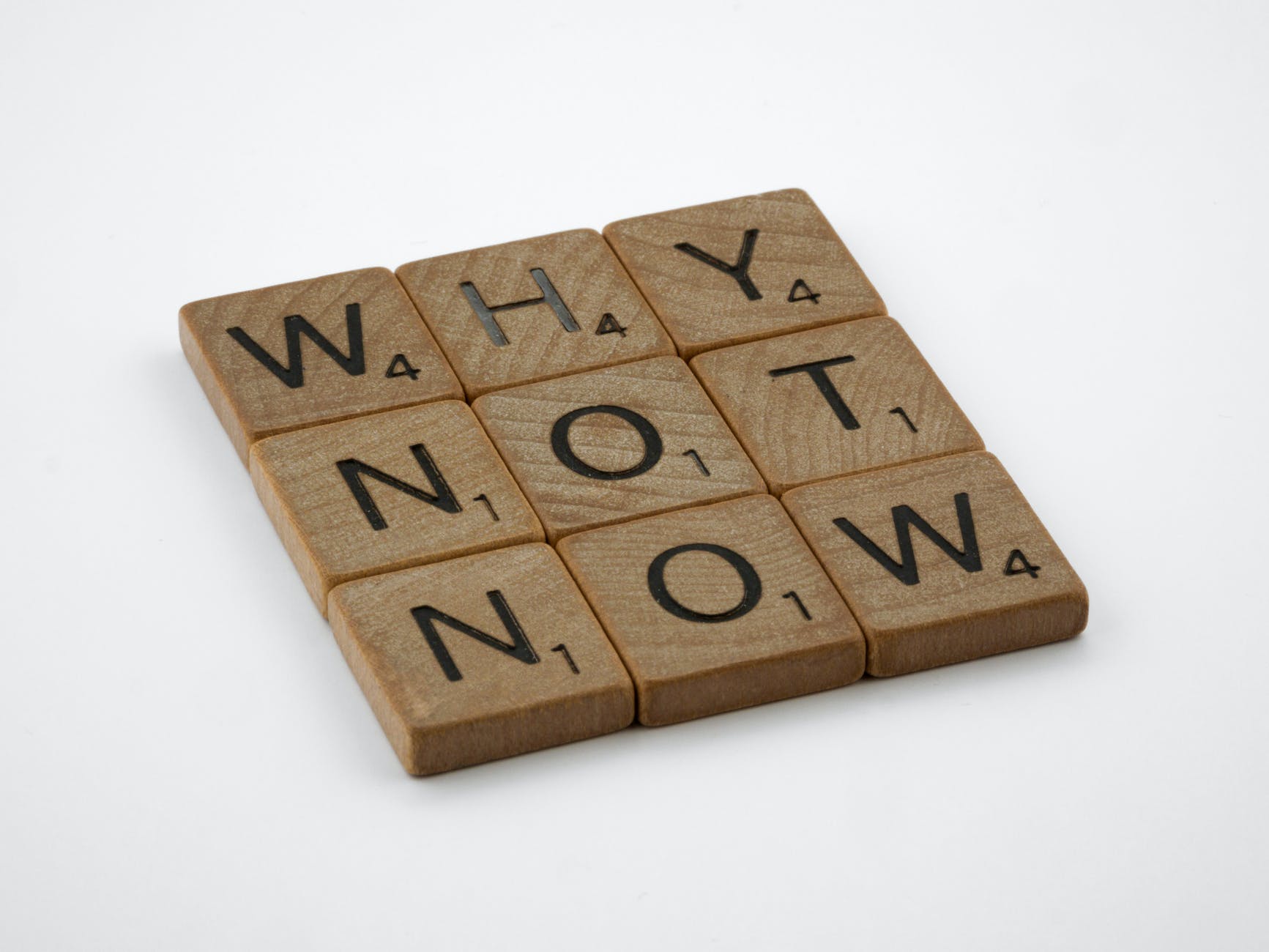 Scrabble tiles spelling out the words "Why not now"
